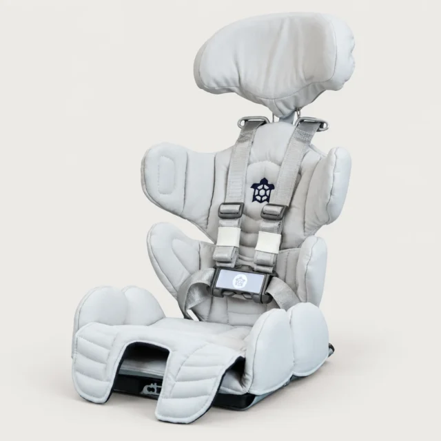 Tarta Kid Seating System paediatric chair shown at a three-quarter angle, with adjustable headrest, harness, and turtle logo padding